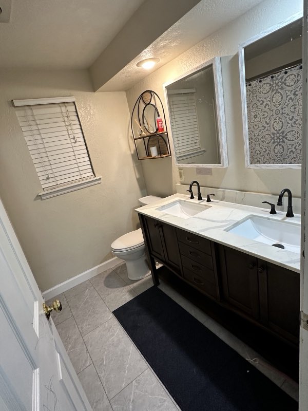 Finished bathroom with a double-sink vanity, marble-look countertop and new tile floor
